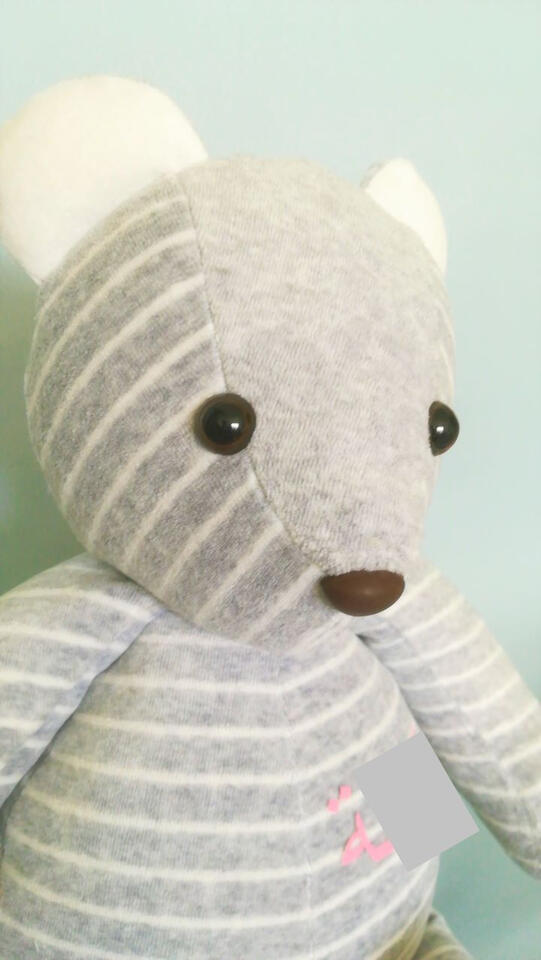 Ein Erinnerungsbär / Memory Bear aus einer hellgrauen geringelten Nicki-Jacke mit rosa Aufdruck